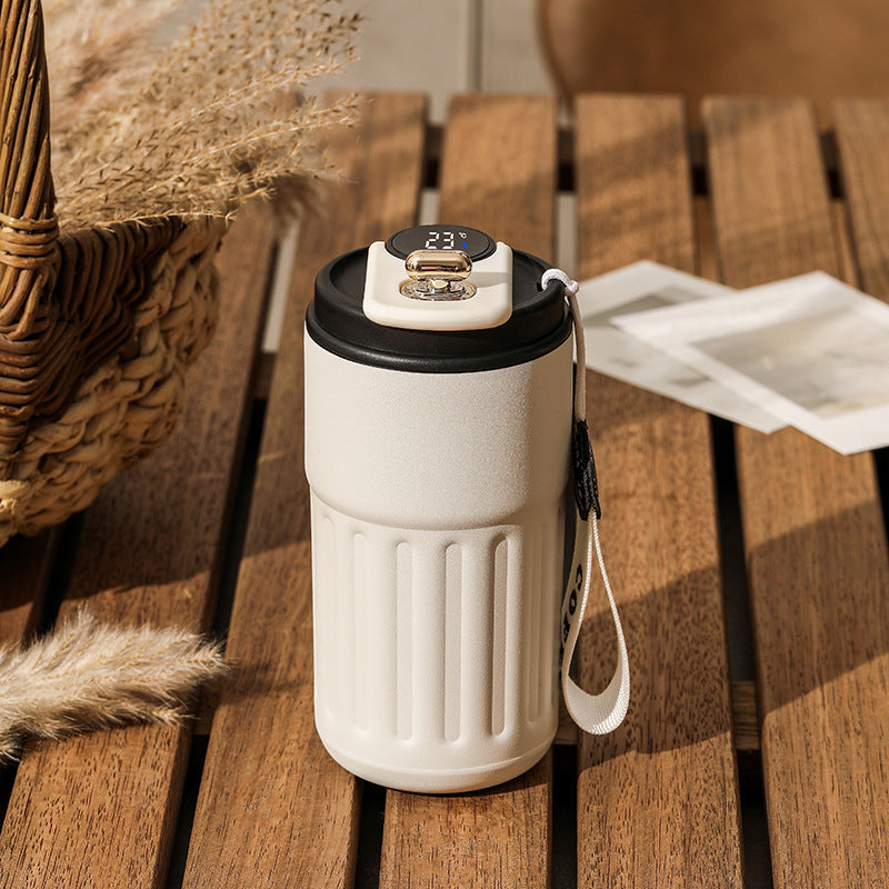 White and black thermos with temperature display on a wooden table.