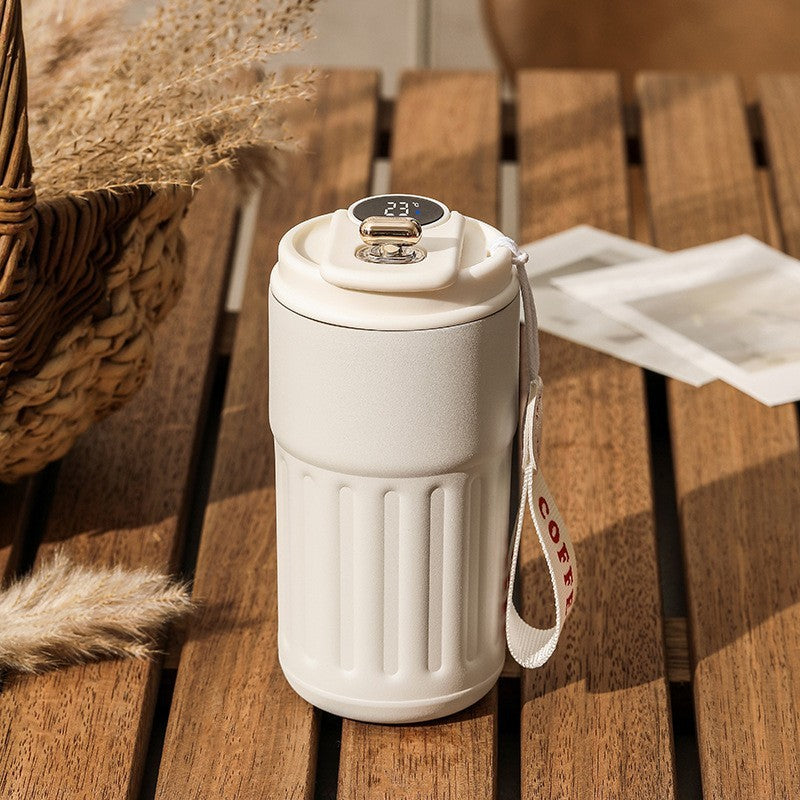 Cream colored temperature-controlled coffee mug on wooden table.