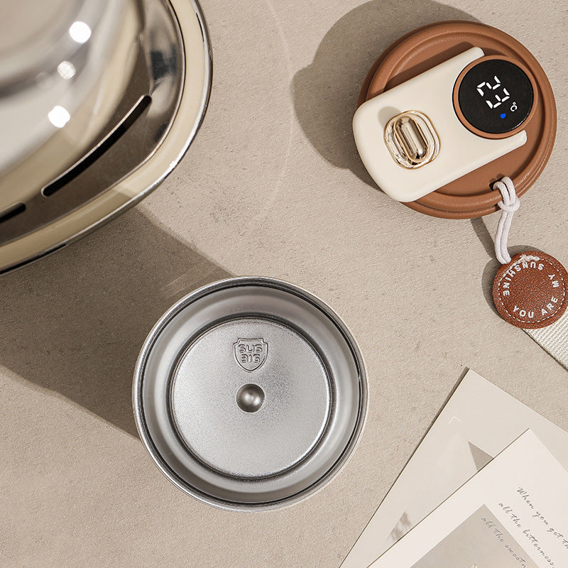 Overhead shot of a metal container with the "SUS 316" logo, a temperature indicator on a brown and white coaster, and greeting cards.