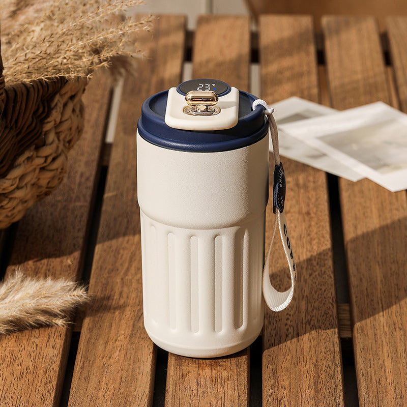 White insulated cup with a digital display on a wooden table.