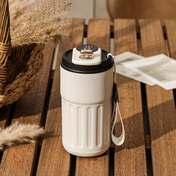 White and black thermos with temperature display on a wooden table. 
